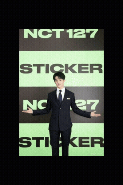A Man In A Suit Is Standing In Front Of A Sign That Says Nct127 Sticker GIF