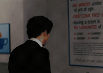 A Man In A Suit Is Standing In Front Of A Sign That Says " No Smoking " GIF
