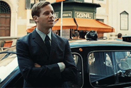 A Man In A Suit Is Standing In Front Of A Store That Says Giorni GIF