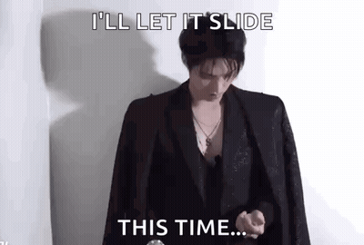 A Man In A Suit Is Standing In Front Of A Wall And Saying `` I 'Ll Let It Slide This Time ... '' . GIF