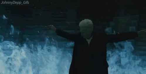 A Man In A Suit Is Standing In Front Of A Wall Of Flames . GIF