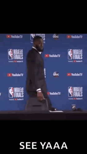 a man in a suit is standing in front of a wall that says nba finals on it