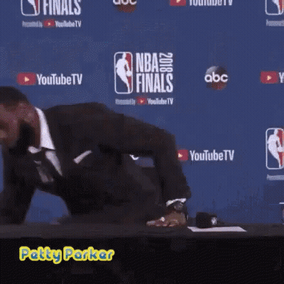 A Man In A Suit Is Standing In Front Of A Wall That Says Nba Finals On It GIF
