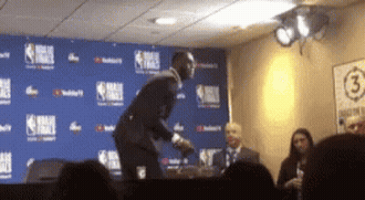 A Man In A Suit Is Standing In Front Of A Wall With The Number 3 On It GIF