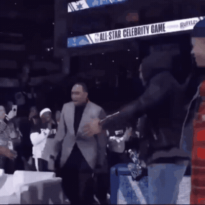 A Man In A Suit Is Standing In Front Of An All Star Celebrity Game Sign GIF