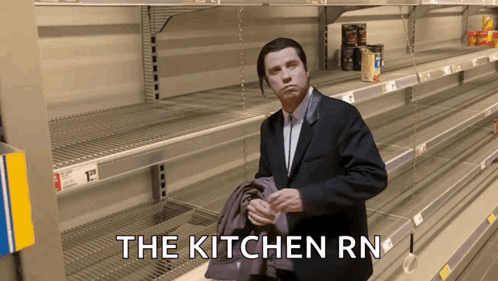 A Man In A Suit Is Standing In Front Of Empty Shelves With The Words " The Kitchen Rn " GIF