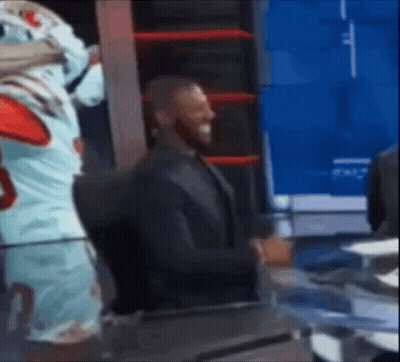 A Man In A Suit Is Standing Next To A Mascot In A Boxing Ring . GIF