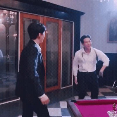 A Man In A Suit Is Standing Next To A Pool Table . GIF
