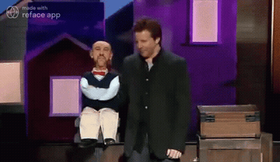A Man In A Suit Is Standing Next To A Puppet . GIF