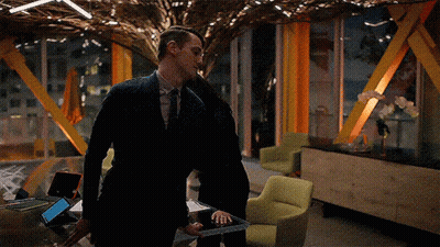 A Man In A Suit Is Standing Next To A Woman Holding A Tablet GIF