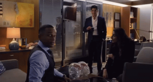 A Man In A Suit Is Standing Next To A Woman In A Black Dress GIF