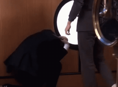 A Man In A Suit Is Standing Next To A Woman In A Black Dress . GIF