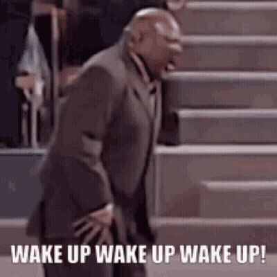 A Man In A Suit Is Standing On A Set Of Stairs And Says `` Wake Up Wake Up Wake Up '' . GIF