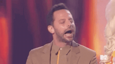 A Man In A Suit Is Standing On A Stage With His Mouth Open And Holding A Trophy . GIF