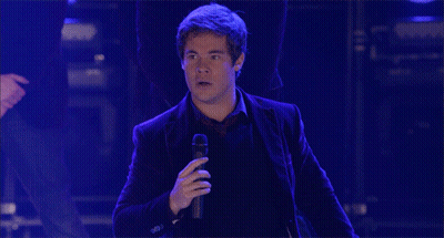 A Man In A Suit Is Standing With His Arms Outstretched GIF