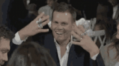 A Man In A Suit Is Surrounded By People While Holding A Drink . GIF