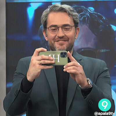 A Man In A Suit Is Taking A Picture Of Himself With A Phone With The Letter H On It GIF