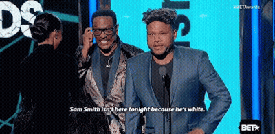 A Man In A Suit Is Talking Into A Microphone While Standing Next To Another Man . GIF