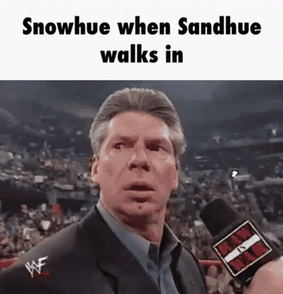 A Man In A Suit Is Talking Into A Microphone With The Words Snowhue When Sandhue Walks In Above Him GIF