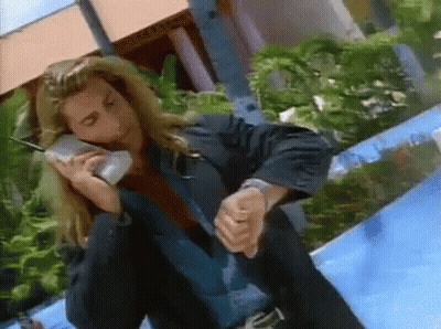 A Man In A Suit Is Talking On A Cell Phone And Checking His Watch GIF