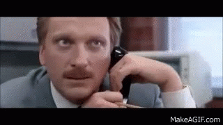 A Man In A Suit Is Talking On A Cell Phone . GIF