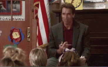 A Man In A Suit Is Talking To A Group Of Children In Front Of An American Flag . GIF