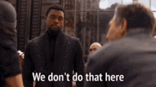 A Man In A Suit Is Talking To A Group Of Men And Says `` We Don T Do That Here '' . GIF