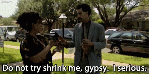 A Man In A Suit Is Talking To A Woman Who Is Holding A Gun And Says Do Not Try Shrink Me Gypsy GIF
