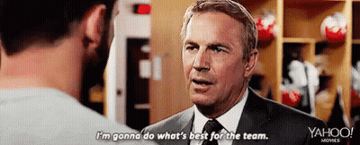 A Man In A Suit Is Talking To Another Man In A Locker Room . GIF