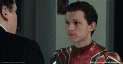 A Man In A Suit Is Talking To Another Man In A Spider Man Suit GIF