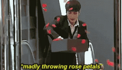 A Man In A Suit Is Throwing Rose Petals At The Camera GIF