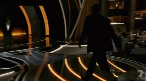 A Man In A Suit Is Walking Across A Stage With A Live Sign On It GIF