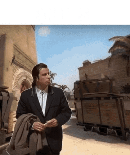 A Man In A Suit Is Walking Down A Desert Road GIF