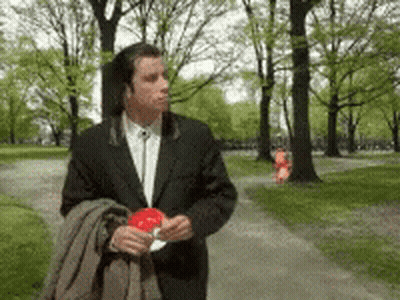 A Man In A Suit Is Walking Down A Path Holding A Lollipop GIF