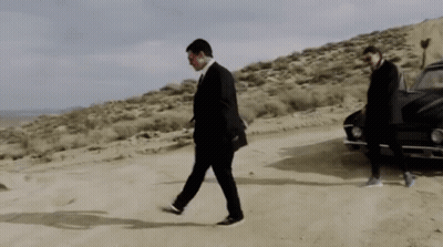 A Man In A Suit Is Walking In The Desert GIF