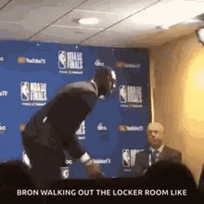 A Man In A Suit Is Walking Out Of A Locker Room Like A Basketball Player . GIF