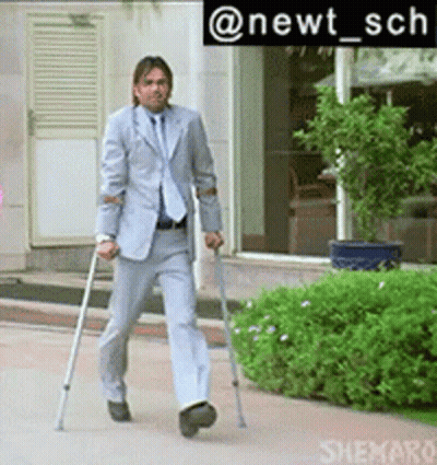 A Man In A Suit Is Walking With Crutches In Front Of A Building GIF
