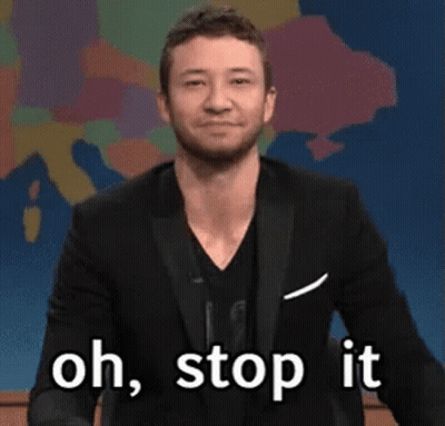 A Man In A Suit Is Waving His Hand And Saying Oh Stop It GIF