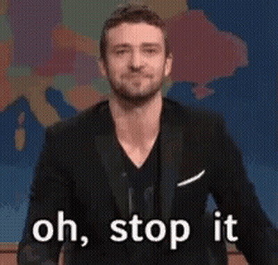 A Man In A Suit Is Waving His Hand And Saying Oh Stop It GIF