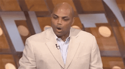 A Man In A Suit Is Yawning While Standing In Front Of A Microphone On A Stage . GIF