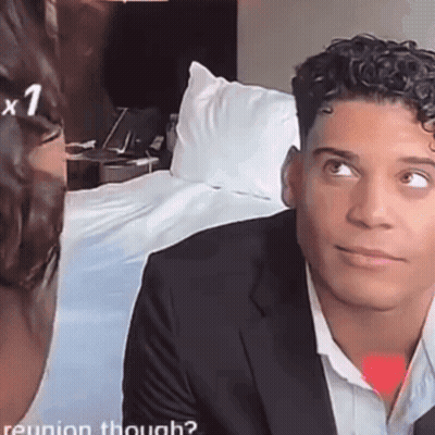 A Man In A Suit Looks At A Woman In A White Shirt . GIF
