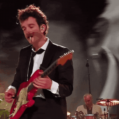 A Man In A Suit Plays A Red Guitar GIF