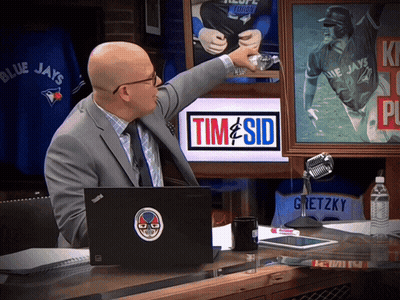 A Man In A Suit Points To A Picture Of A Blue Jays Baseball Player GIF