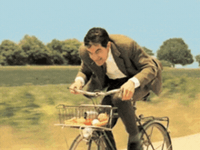 A Man In A Suit Rides A Bike With A Basket Full Of Food GIF