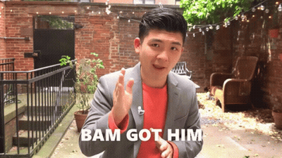 A Man In A Suit Says Bam Got Him While Standing In Front Of A Brick Wall GIF