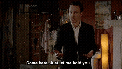 A Man In A Suit Says Come Here Just Let Me Hold You In A Living Room GIF