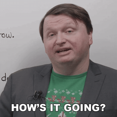 A Man In A Suit Says How 'S It Going In Front Of A White Board GIF