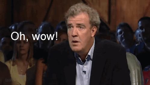 A Man In A Suit Says " Oh Wow " In Front Of A Crowd Of People GIF
