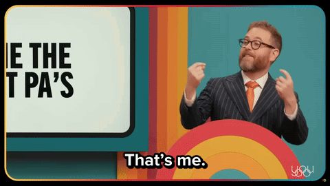 A Man In A Suit Says That 'S Me In Front Of A Rainbow GIF