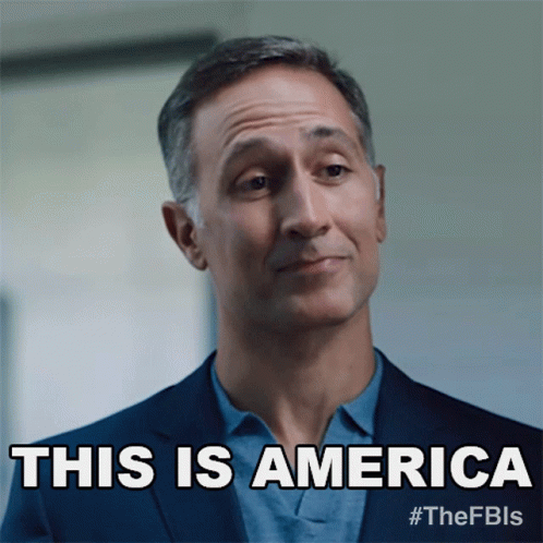 A Man In A Suit Says " This Is America " In Front Of His Face GIF
